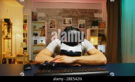 POV de jeune homme en colère portant un casque de réalité virtuelle après avoir perdu à des jeux en ligne. Contrôleur sans fil. Banque D'Images