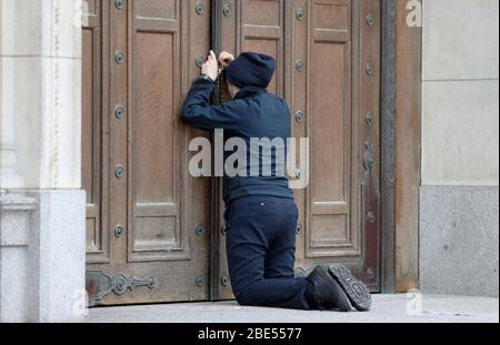 Une femme prie à la porte fermée de la cathédrale de Westminster devant la messe du matin de Pâques, Londres, alors que le Royaume-Uni continue de se verrouiller pour aider à freiner la propagation du coronavirus. Les églises de tout le pays continuent de diffuser des services numériques jusqu'à Pâques, avec plus de 1 000 direct régulièrement. Banque D'Images