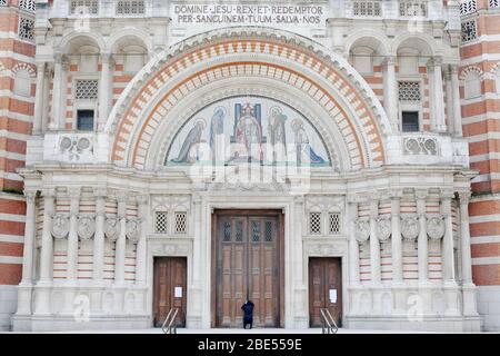 Une femme prie à la porte fermée de la cathédrale de Westminster devant la messe du matin de Pâques, Londres, alors que le Royaume-Uni continue de se verrouiller pour aider à freiner la propagation du coronavirus. Les églises de tout le pays continuent de diffuser des services numériques jusqu'à Pâques, avec plus de 1 000 direct régulièrement. Banque D'Images