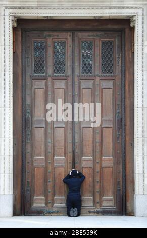 Une femme prie à la porte fermée de la cathédrale de Westminster devant la messe du matin de Pâques, Londres, alors que le Royaume-Uni continue de se verrouiller pour aider à freiner la propagation du coronavirus. Les églises de tout le pays continuent de diffuser des services numériques jusqu'à Pâques, avec plus de 1 000 direct régulièrement. Banque D'Images