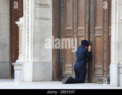 Une femme prie à la porte fermée de la cathédrale de Westminster devant la messe du matin de Pâques, Londres, alors que le Royaume-Uni continue de se verrouiller pour aider à freiner la propagation du coronavirus. Les églises de tout le pays continuent de diffuser des services numériques jusqu'à Pâques, avec plus de 1 000 direct régulièrement. Banque D'Images