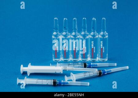 Seringues et ampoules à médicaments sur fond bleu. Sur ampoules de vaccin écrit contre le coronavirus. Concept de santé. Banque D'Images