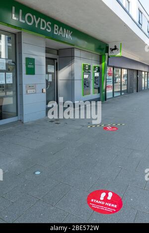 10 avril 2020. Au cours de la pandémie Covid-19 du coronavirus de 2020, un verrouillage est en place au Royaume-Uni, et les gens ne permettent de sortir que pour des raisons spécifiques. Dans le centre-ville de Farnborough, dans le Hampshire, la succursale de Lloyds Bank a placé des marqueurs à l'extérieur sur le trottoir à deux mètres de distance pour aider les gens à observer des distances sociales sûres lors de la file d'attente pour entrer dans la banque. Banque D'Images