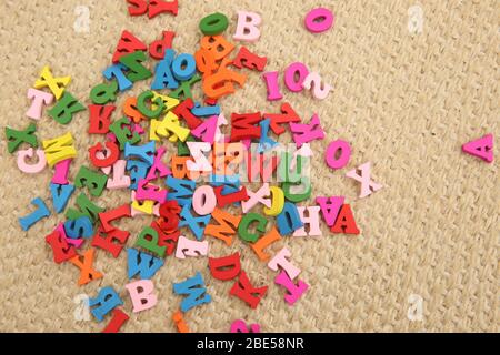 Lettres en bois multicolores en rouge, vert, bleu, rose et jaune. Les lettres sont un jouet pour enfants et sont dispersées sur le sol. C'est une façon amusante de le faire Banque D'Images