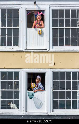 Appledore, North Devon, Royaume-Uni. Dimanche de Pâques 12 avril 2020. Les habitants d'Appledore, Angie Copleston et Kelly Benjamin vêtus de costumes de lapin, font le plus d'isolement le dimanche de Pâques en se donnant les autres œufs de Pâques, les plaçant dans un filet de crabes et les élever et les abaisser entre leurs fenêtres du dernier étage . Crédit: Terry Mathews/Alay Live News Banque D'Images