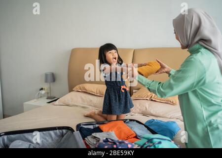 la fille donne des vêtements à sa mère qui prépare les vêtements à mettre dans la valise Banque D'Images