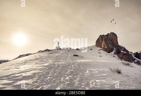 Randonneur debout sur le rocher avec les bâtons de trekking en profitant de la vue des montagnes de neige au lever du soleil Ciel dramatique. Banque D'Images