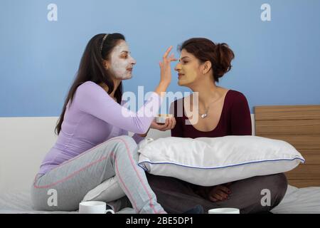 Jeune femme appliquant un pack de visage sur le visage de sa sœur. Banque D'Images