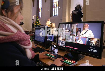 Magdeburg, Allemagne. 12 avril 2020. Une femme contrôle l'apparence Internet transmise en direct de la masse de Pâques de l'évêque Gerhard Feige en raison des mesures contre le nouveau virus corona de l'église catholique romaine Saint-Sébastien. Le diocèse offre des services de culte par direct depuis plusieurs semaines et rencontre ainsi des réactions positives des fidèles. Crédit: Ronny Hartmann/dpa/Alay Live News Banque D'Images