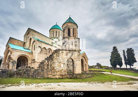Femme marche à la chapelle de la tour de l'église Bagrati à ciel couvert à Kutaisi, Géorgie Banque D'Images