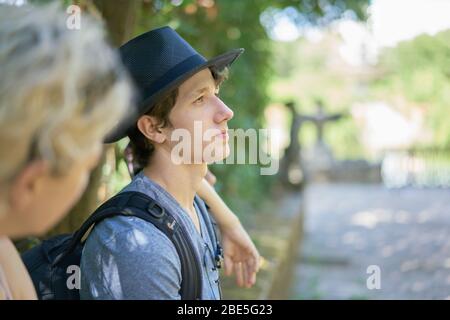 Gros plan d'un jeune homme triste et pensif assis dans la verdure d'un parc Banque D'Images