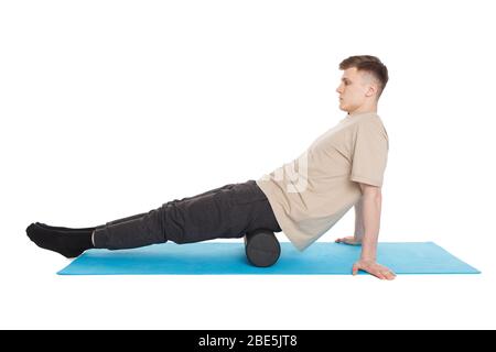 Un homme de handsome montre des exercices utilisant un rouleau en mousse pour un massage de libération myofasciale des points de déclenchement. Massage des fesses. Isolé sur blanc. Banque D'Images