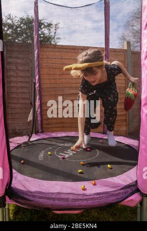 Emily,9, sur une chasse aux œufs le dimanche de Pâques, confinée à son jardin arrière à Bromley, dans le sud de Londres, alors que le Royaume-Uni continue de se maintenir en place pour aider à freiner la propagation du coronavirus. Banque D'Images