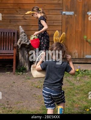 Benjamin,3, et Emily,9, sur une chasse aux œufs le dimanche de Pâques, confiné à son jardin arrière à Bromley, dans le sud de Londres, comme le Royaume-Uni continue de se maintenir pour aider à freiner la propagation du coronavirus. Banque D'Images