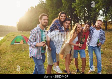 Groupe de personnes souriant debout sur une fête pique-nique avec une tente sur la nature en été en automne. Banque D'Images