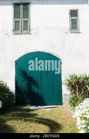 Détail d'une vieille porte et fenêtres dans une ferme des 800, avec un jardin autour et l'ombre des palmiers reflétés Banque D'Images