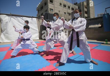 Palestine, bande de Gaza ville de Rafah. 12 avril 2020. Khaled Sheikh Al-Eid (C), instructeur de Karate palestinien, s'entraîne avec ses enfants, tous portant des masques de visage en raison de la COVID-19, sur leur toit, dans la ville de Rafah, dans le sud de la bande de Gaza, le 12 avril 2020. Crédit: Khaled Omar/Xinhua/Alay Live News Banque D'Images