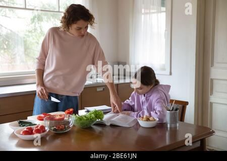 Maman aidant la fille adolescente avec des études de cuisine à table de cuisine Banque D'Images