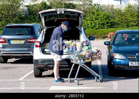 Supermarché Tesco, Hove, Royaume-Uni, 2020. Un homme âgé décharge ses achats en portant un masque facial pour la sécurité à la suite de la pandémie de coronavirus. Banque D'Images