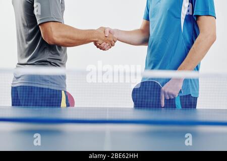 Image recadrée des joueurs de tennis de table se secouant les mains avant de jouer au jeu Banque D'Images