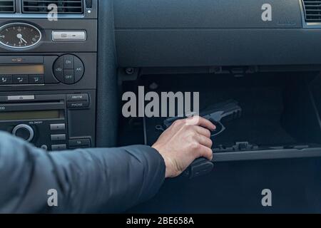 le conducteur prend le pistolet de l'habitacle de la voiture. Gangster ou policier Banque D'Images