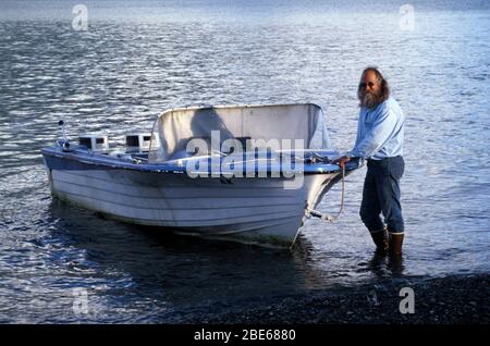 L'homme senior avec barbe longue maintient le bateau-taxi passager en place avec une corde attendant les passagers à l'extérieur d'un pavillon à Sadie Cove, Homer, Alaska, États-Unis Banque D'Images