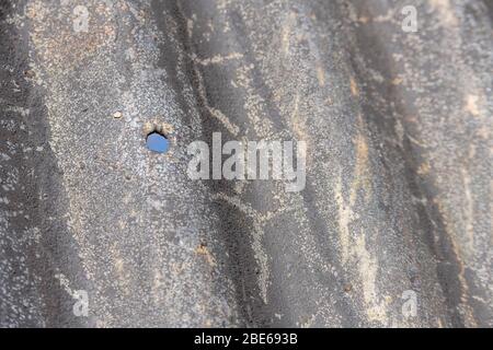 Tôle d'acier ondulé qui a vu de meilleurs jours et trou de boulon de fixation. Banque D'Images