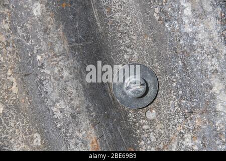 Tôle d'acier ondulé qui a vu de meilleurs jours et tête de boulon de fixation avec rondelle métallique. Banque D'Images