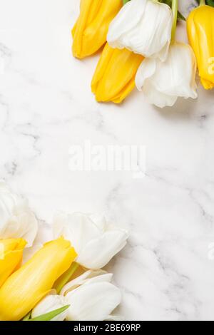 Fond de la fête des mères avec tulipes blanches et jaunes sur table en marbre. Concept de printemps. Espace de copie Banque D'Images