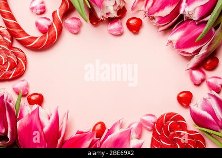 Bonbons en forme de coeur avec tulipes pivoines sur fond rose. Concept de Saint Valentin. Espace de copie Banque D'Images