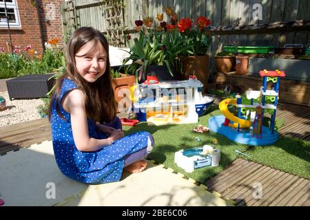 Jeune fille jouant avec playmobil dans le jardin Banque D'Images