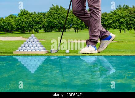 Joueur de golf pratiquant dans un terrain d'exercice avec pyramide de balles de golf Banque D'Images