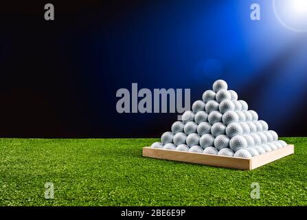 Pyramide de balles de golf dans un terrain de conduite avec lumière bleue brillant, image horizontale Banque D'Images