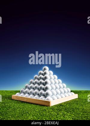 Pyramide de balles de golf dans un terrain de conduite avec lumière bleue brillant, image verticale Banque D'Images