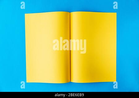 Feuille jaune de papier de type A 3 pliée au milieu dans une planche sur un fond bleu avec un endroit pour le texte Banque D'Images