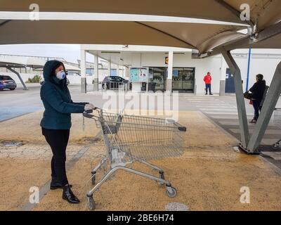 Portugal Faro 2020 8 - avril: Femme avec un panier debout en ligne dans un magasin de shopping dans la rue pendant le virus covid 19. Banque D'Images