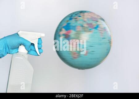 Avec un globe et un désinfectant, vous pouvez le porter dans un gant médical. Concept de foyer COVID-19. Banque D'Images