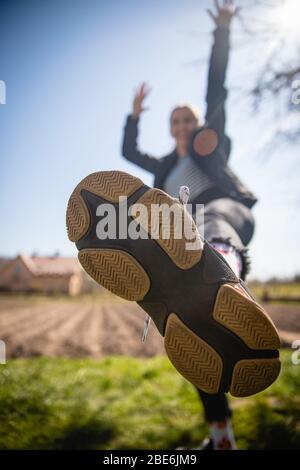 Semelle de sneakers revêtue de joyeuses filles dansant, sautant et célébrant le succès avancez dans la lumière vive Banque D'Images