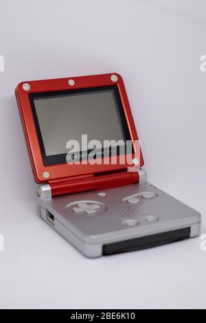 Game boy Advanced SP portable tenu console de jeu par Nintendo de 2003 en argent rouge Super Mario édition. Ouvert, éteint avec le jeu inséré sur blanc Banque D'Images