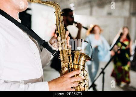 Vue de concert d'un saxophone avec chanteur et groupe musical de jazz en arrière-plan Banque D'Images