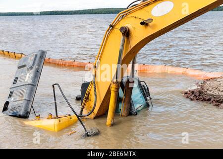 Une pelle hydraulique jaune (équipement de construction) s'est noyée sur le lac tout en travaillant à renforcer le rivage. Violation de sécurité. Urgence à contrainte Banque D'Images