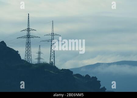 Montagnes avec tours de transmission haute tension le matin Mist Banque D'Images