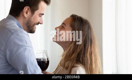 Couple de jeunes familles épris et émotif à boire du vin à l'intérieur. Banque D'Images