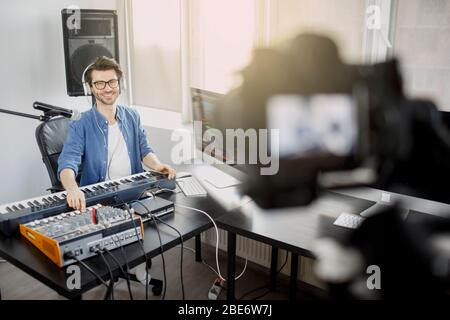 Le blogueur vidéo en direct enseigne comment faire des morceaux de musique en direct. Vidéo pour réseau social ou diffusion. DJ dans le studio de diffusion. Producteur de musique est Banque D'Images