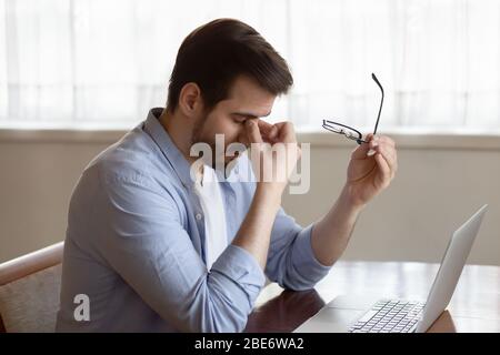 Un jeune homme d'affaires stressé qui prend des lunettes, souffrant de tensions oculaires. Banque D'Images