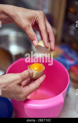 Les mains de la femme séparant le jaune d'œuf des blancs Banque D'Images