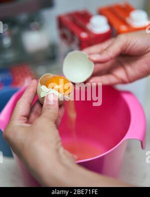 Les mains de la femme séparant le jaune d'œuf des blancs Banque D'Images