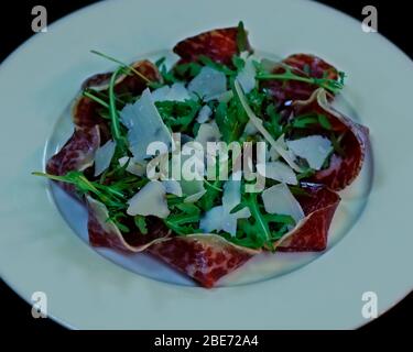 Carpaccio de boeuf ( fines tranches de boeuf ) avec feuilles de roket et fromage parmeesan, plats italiens de départ Banque D'Images