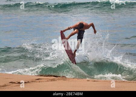 Photo à haute énergie d'un jeune homme sur un skim board à la plage. Banque D'Images