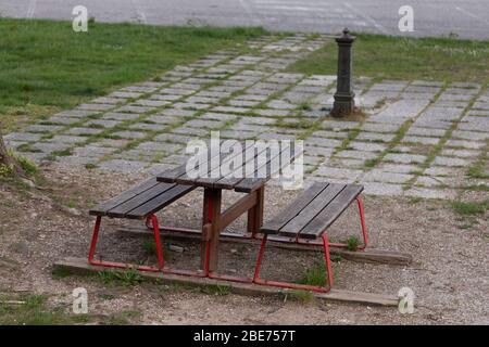 Banc et table rustiques vacants dans un parc urbain déserté en grand angle avec espace de copie en raison du maintien du coronavirus ou de la pandémie de Covid-19 Banque D'Images